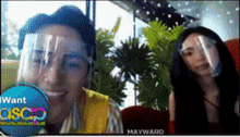 a man wearing a face shield and a woman wearing a face shield are on a video call with mayward