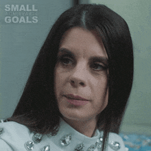 a woman in a white top with small achievable goals written on the bottom