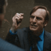 a man in a suit and tie talks to another man in a dark room