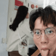 a man wearing glasses sticks his tongue out in front of a woman