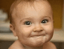 a baby is making a funny face and looking at the camera .