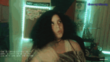 a woman stands in front of a wall that says happy halloween
