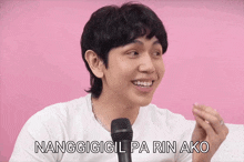 a man in a white shirt is smiling and talking into a microphone with the words nanggigigil pa rin ako above him