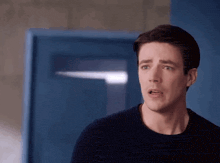 a man in a black shirt is standing in front of a blue door .
