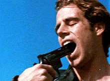 a man is holding a gun in his mouth with a blue sky in the background