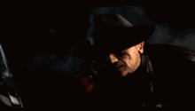a man in a hat is holding a gun and smiling at the camera