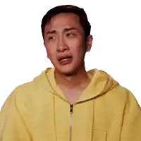a man wearing a yellow hoodie is making a sad face