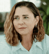 a close up of a woman 's face with a white shirt and earrings