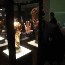 a man with glasses looks at a trophy in a glass case