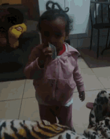 a little girl in a pink jacket holds a piece of paper