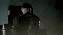a man in a red hat is holding a flashlight in a dark room .