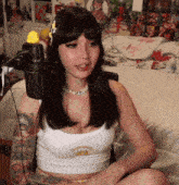 a woman in a white tank top is sitting in front of a microphone .