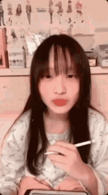 a young girl with long hair is holding a pen in her hand and looking at the camera .