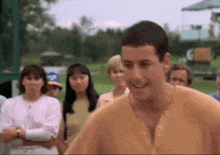 a man in a yellow shirt is smiling in front of a group of people