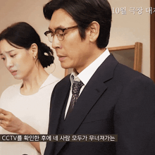a man in a suit and tie stands next to a woman who is looking at her phone