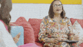 a woman with glasses is sitting on a couch with a laptop