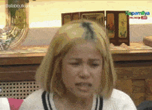 a woman with blonde hair is sitting in front of a sign that says kapamilya on it
