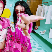 a woman in a pink dress and sunglasses is pointing at the camera .