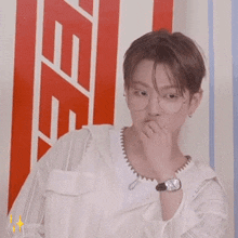 a man wearing glasses and a watch is standing in front of a red and white striped wall .