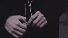 a close up of a person 's hands tying a pair of earphones .