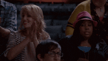 a woman in a pink hat sits in a crowd