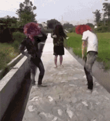 a group of people wearing clown costumes are standing on a sidewalk in the mud .