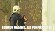 a fireman wearing a helmet is standing in front of a door holding a folder .