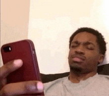 a man is laying on a couch looking at his phone .