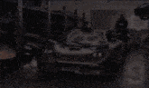 a man in a black hoodie stands next to a black sports car
