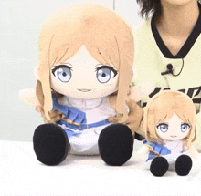 two stuffed dolls are sitting next to each other on a table and one has blue eyes