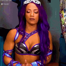 a female wrestler with purple hair and sunglasses is sitting in a locker room .