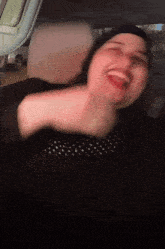 a woman in a black polka dot shirt is laughing