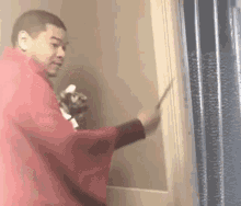 a man in a red robe is standing next to a door holding a sword .