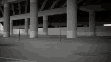 a black and white photo of an empty parking lot under a highway