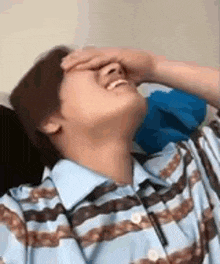 a man is covering his face with his hand while laughing .