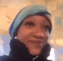 a woman wearing a blue hat and a black jacket is smiling .