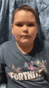 a young boy wearing a fortnite shirt is making a funny face