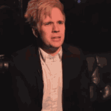 a man in a suit and white shirt is sitting on a black couch