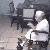 an elderly woman is sitting in a wheelchair in front of a dining table .