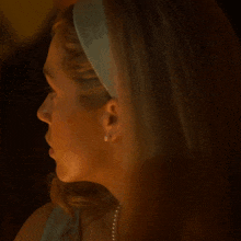a close up of a woman 's face with her eyes closed and a pearl necklace