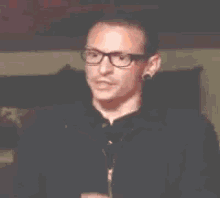 a man wearing glasses is holding a red light in his hands .