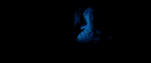 a man in a white shirt is looking at a computer screen in the dark