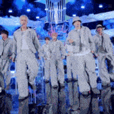 a group of young men are dancing on a stage and one of them is wearing a bucket hat