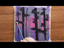 a person is painting a painting of trees with a brush