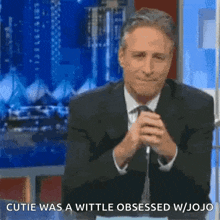 a man in a suit and tie is sitting at a table with his hands folded and says i wish