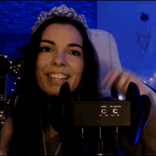 a woman wearing a tiara is sitting in front of a box that says cc