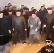 a group of people wearing masks are dancing in a room with a man wearing sunglasses in the foreground .