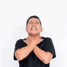 a man in a black shirt is holding his neck in pain .