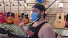 a man wearing a mask in front of a wall of guitars has a shirt that says heavy metal on it