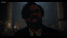a blurry picture of a man in a suit and tie with bbc written on the bottom